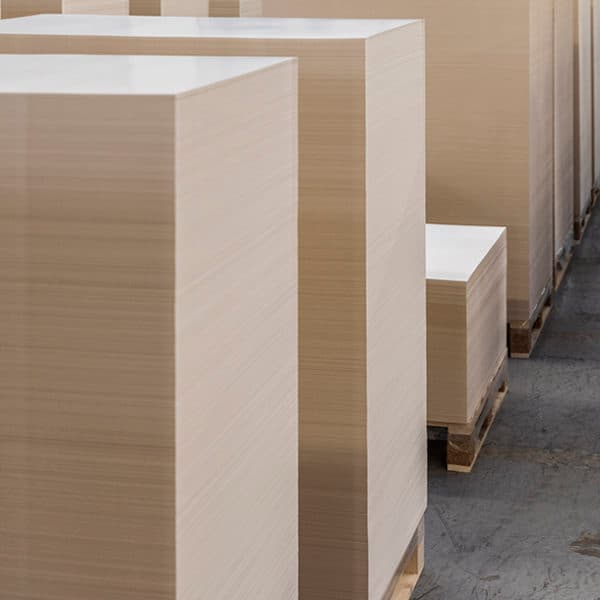 Alte pile di fogli di carta bianca su pallet di legno in un magazzino industriale.