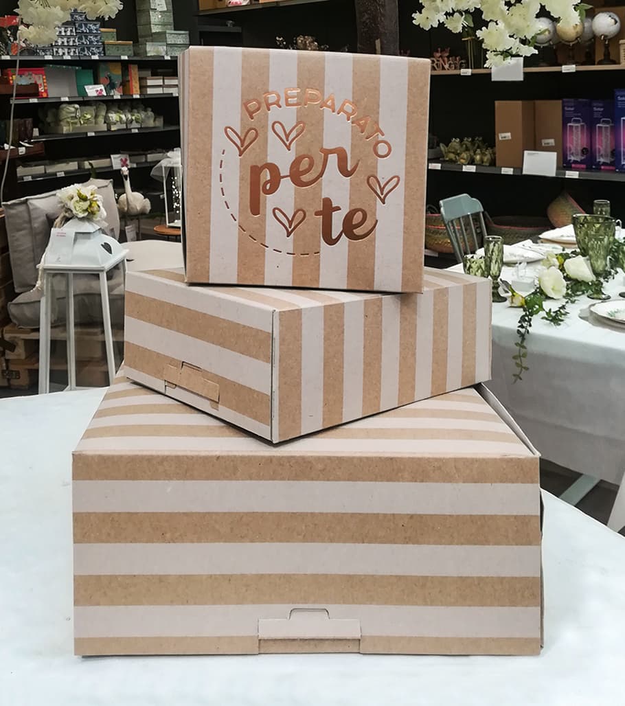 Tre scatole regalo a righe beige e bianche con la scritta "Preparato per te".